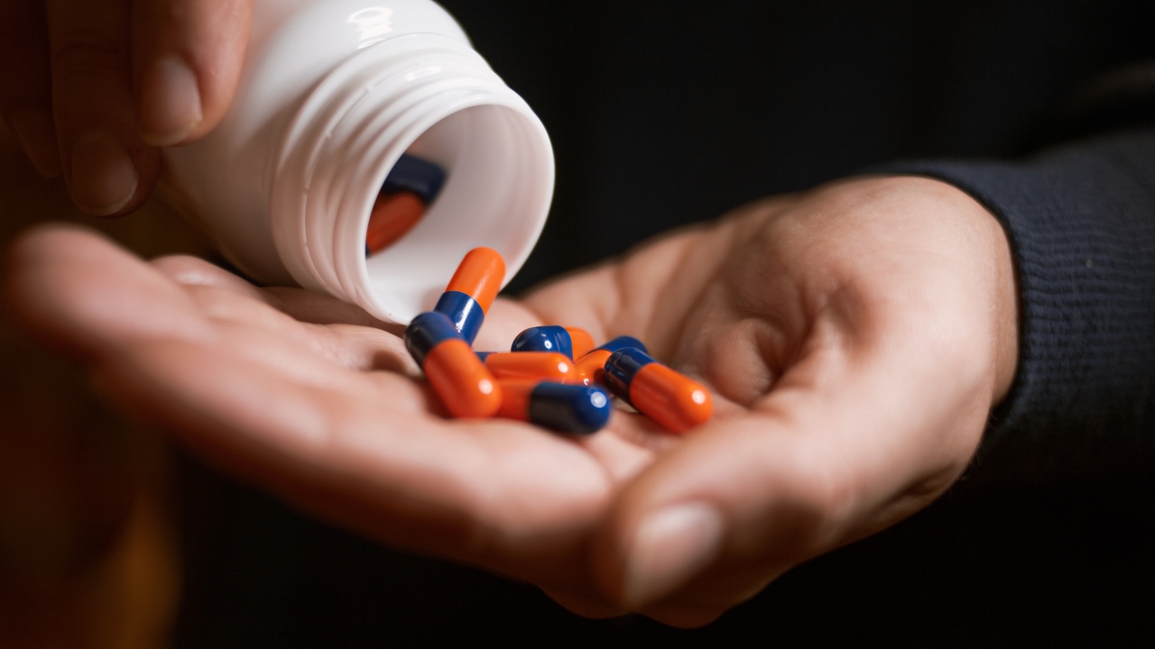 A person pours pills into their hand.