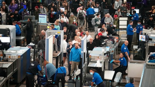 Travelers wait to pass through airport security in Denver