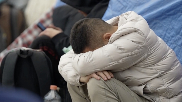 Migrant with his head down on his knees at the U.S.-Mexico border