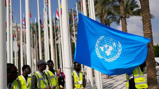 Workers adjust a United Nations flag ahead of the COP28 climate summit