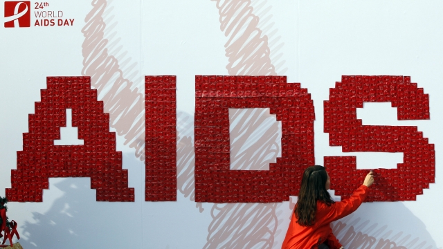 A woman attaches a condom on the board during an AIDS awareness campaign